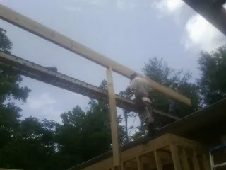 Carpenter setting a ridge beam over a new addition frame — Ice Dam Removal by Roofing Brothers in Auburn