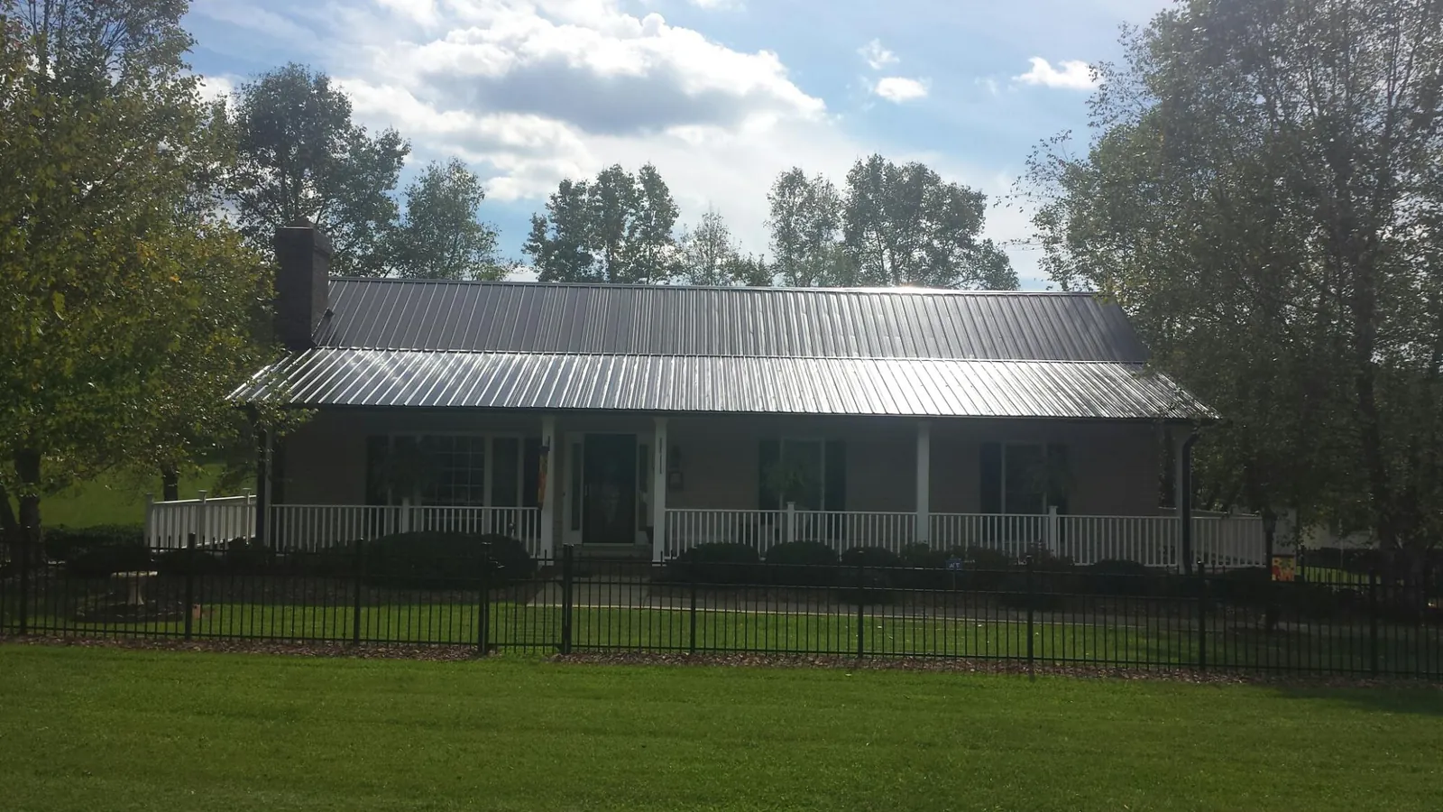 Gray metal roof on a brick ranch with a full width front porch — Gutter Guard Installation work by our crew in Auburn